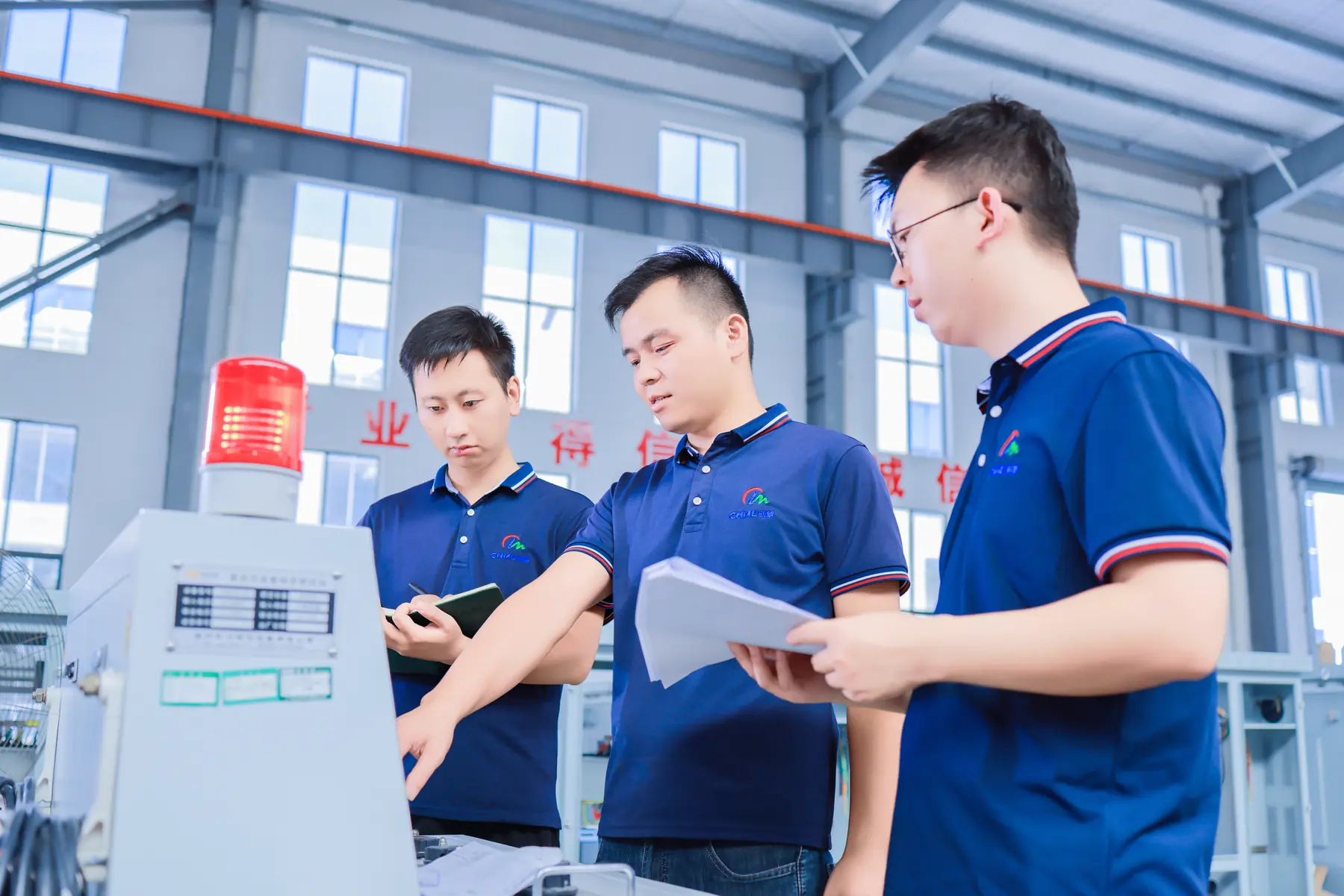 Minglang production employees in company uniforms reviewing work in the factory
